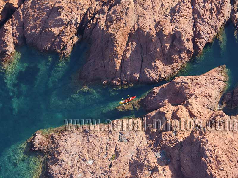 Aerial view of a kayaker on a narrow waterway in the rocky coast of the Estérel Massif, French Riviera. Vue aérienne.