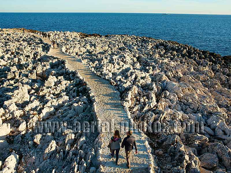 Aerial view of a couple walking in the middle of a geologic curiosity in Saint-Jean-Cap-Ferrat on the French Riviera. Vue aérienne.