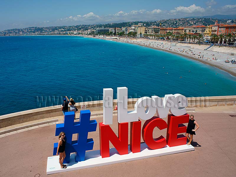 Aerial view of two women posing next to the #ilovenice sign with behind, the famous Promenade des Anglais in Nice Côte d'Azur, France. Vue aérienne.