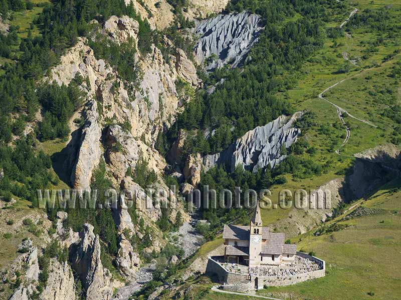 Aerial view of an old church on the rim of a small canyon in Cervières, French Alps, France. Vue aérienne.