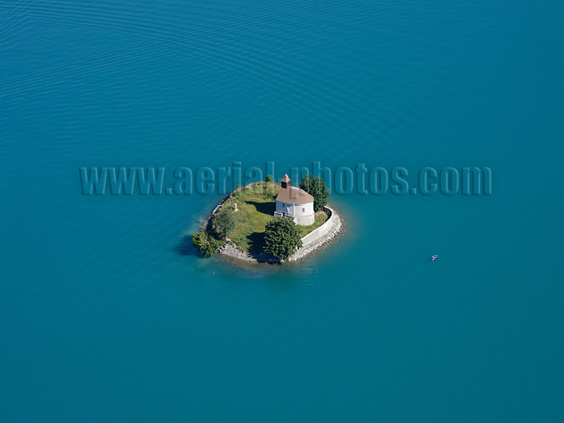 Aerial view of a chapel on a tiny island in the middle of Lake Serre-Ponçon in the French Alps. Vue aérienne.